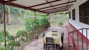 A covered outdoor area with a table and chairs, surrounded by a railing and greenery. - CASA DE CAMPO PRIVADA CON PISCINA (La Mesa)
