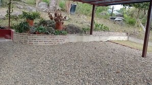 An outdoor covered patio area with gravel flooring, surrounded by brick walls and potted plants. - CASA DE CAMPO PRIVADA CON PISCINA (La Mesa)