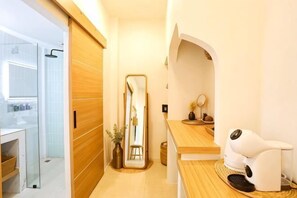 Un baño moderno con tocador de madera, un espejo y una silla de masaje blanca.