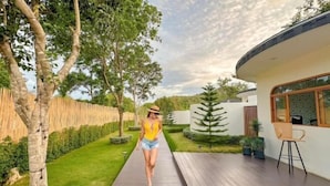 Une maison moderne dotée d’une terrasse en bois, d’un petit espace salon extérieur et d’un jardin bien entretenu.