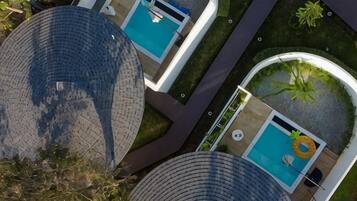 A rooftop pool area with two separate swimming pools, surrounded by a paved deck and greenery.