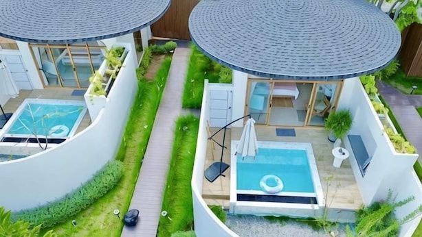 Un bâtiment moderne de forme circulaire, doté d’une piscine, d’une chaise longue et d’un espace de détente abrité.