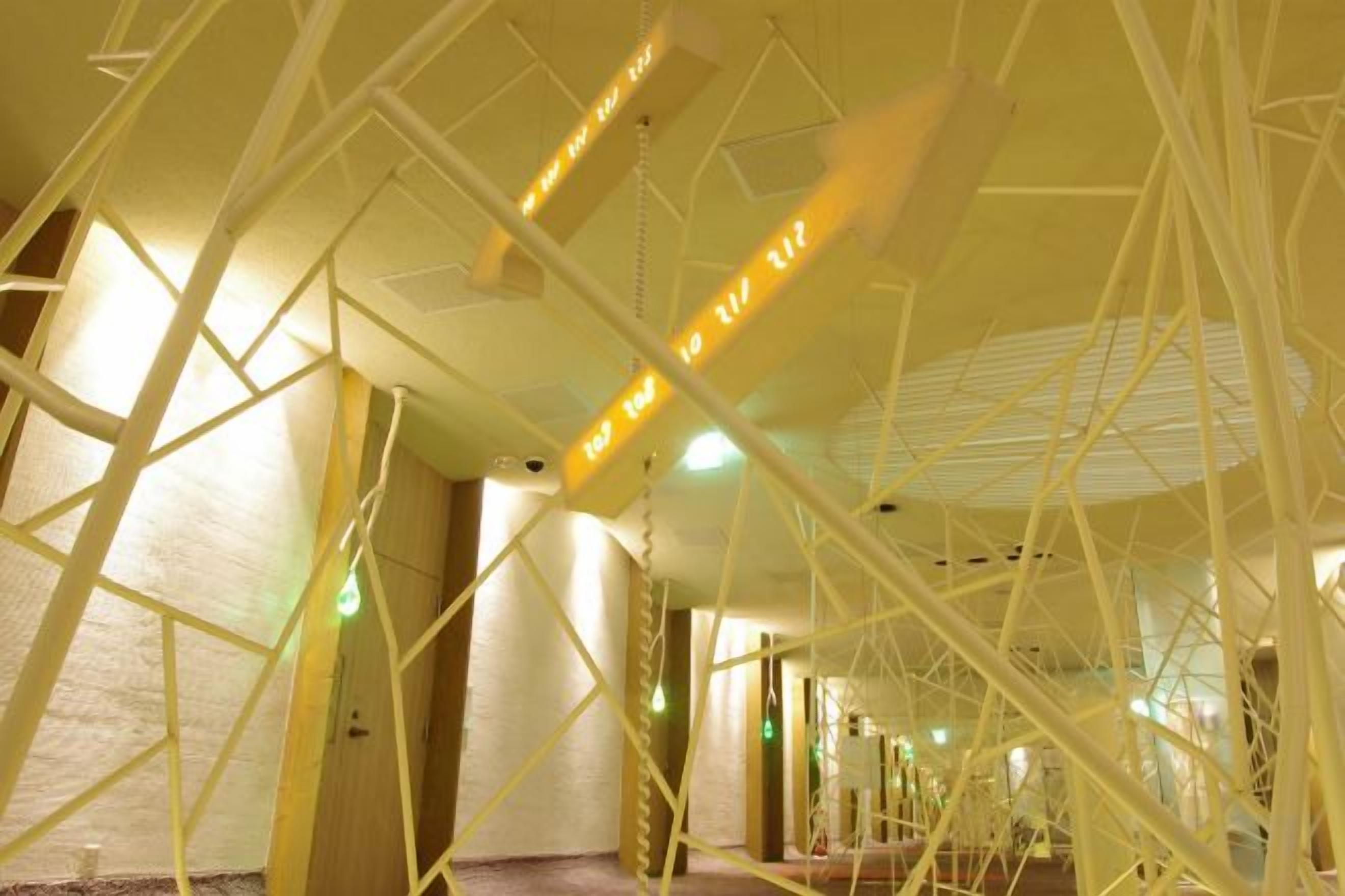 A corridor with geometric ceiling structures and hanging lights.