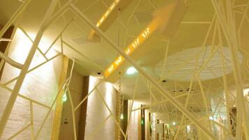 A corridor with geometric ceiling structures and hanging lights.