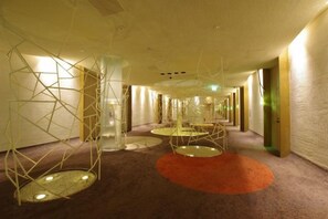 A hotel corridor with a modern design, featuring geometric light fixtures and a carpeted floor. - Blue Hotel Nagi-Adult Only (Otaru)