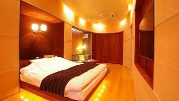 A modern hotel room with a large bed, a bedside table, and a built-in wardrobe.