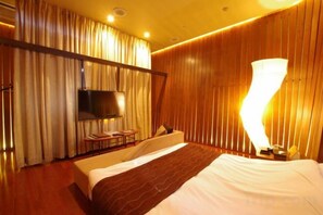 A hotel room with a bed, a TV, a bedside table, and a lamp. - Blue Hotel Nagi-Adult Only (Otaru)