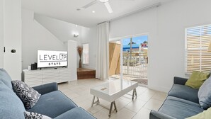 Un salon moderne avec un canapé, une table basse et un téléviseur affichant le message « LEVEL UP STAYS ».