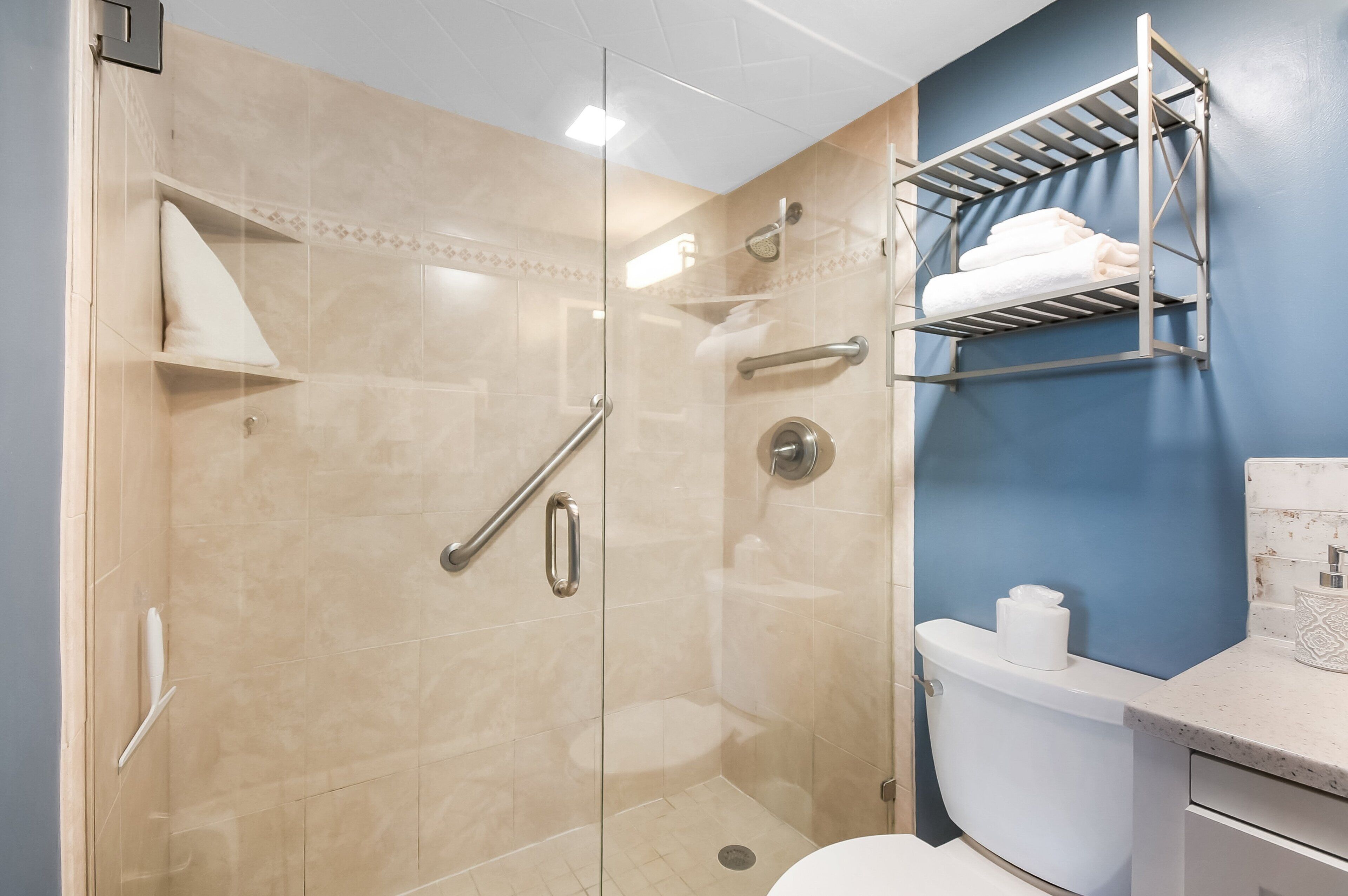 Ein modernes Badezimmer mit einer gläsernen Duschkabine, einer weißen Toilette und einem Handtuchhalter an der Wand.