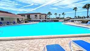 A swimming pool with lounge chairs and palm trees.