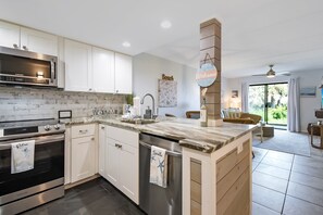 A modern kitchen with white cabinets, a stainless steel range hood, and a built-in oven.