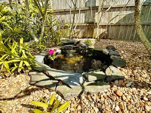 A garden with a pond, surrounded by rocks and plants.