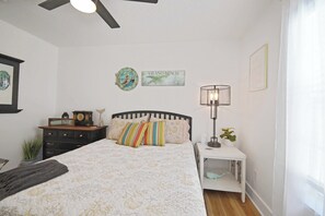 Une chambre à coucher comprenant un lit, une table de chevet, une lampe, une commode et des éléments de décoration murale.