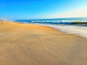 A beach with a clear view of the ocean and a sandy shore.
