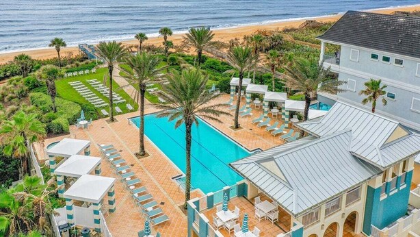Un resort con piscina, sillas de descanso y vistas a la playa.