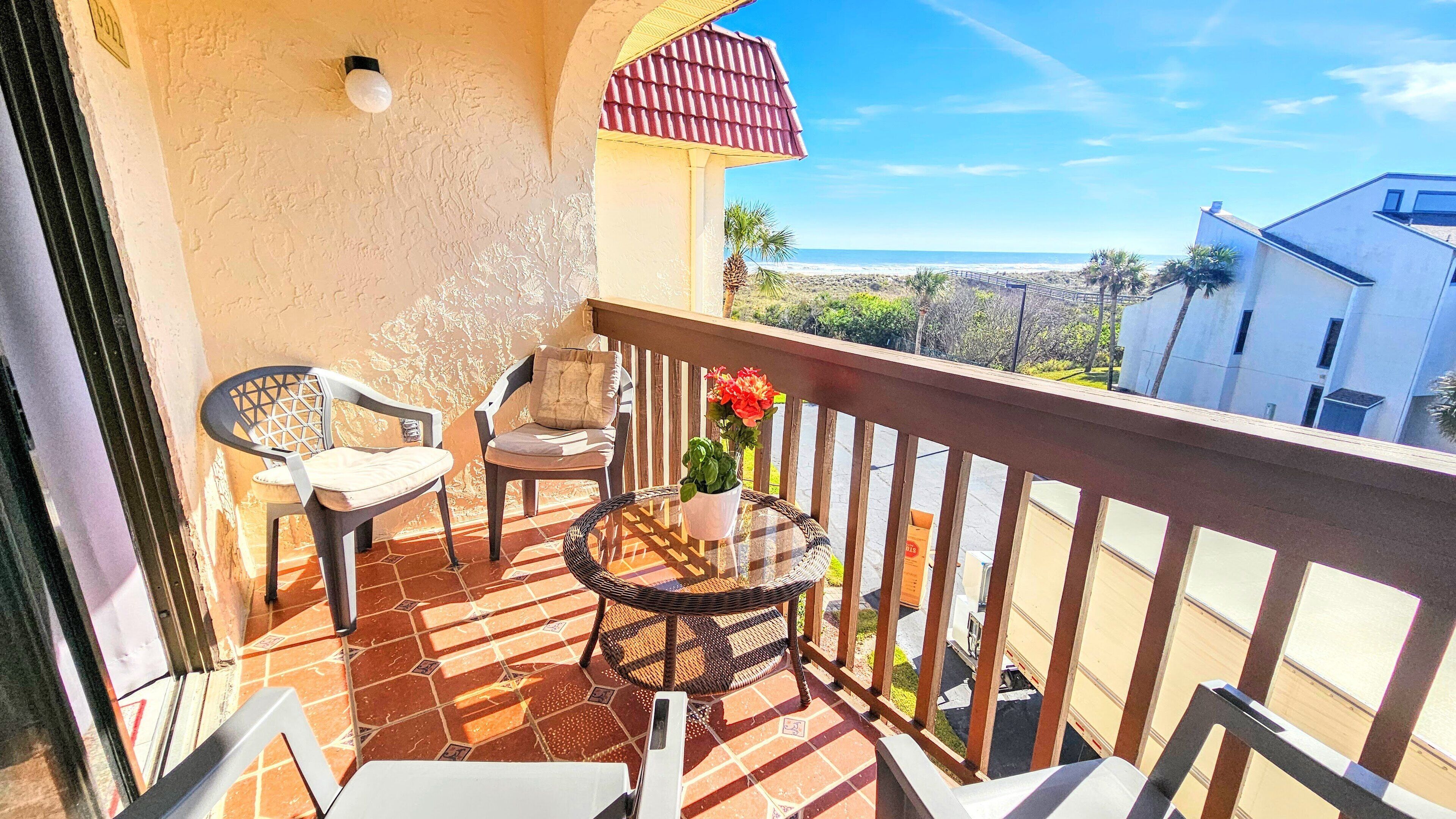 A balcony with two chairs, a small table, and a potted plant.