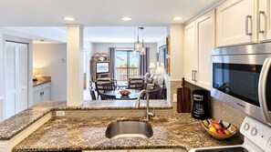 A modern kitchen with granite countertops, stainless steel appliances, and a dining area with a view. - "Casatawaves" Ocean View Villa🌴Awesome Resort Pools! Trolley! (Saint Augustine)