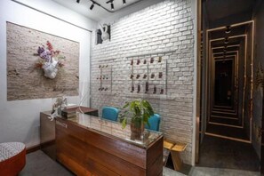 A reception area with a wooden desk, blue chairs, a white brick wall, and a framed artwork. - New York Loft & Japanese Magic by V4Skin (Bangkok)