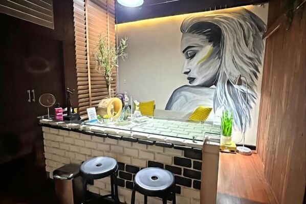 Un espace bar agrémenté d’une fresque murale, de tabourets et d’un comptoir où sont exposés divers objets.