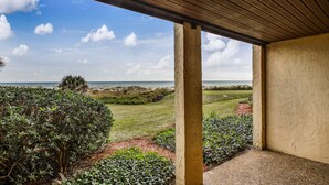 A covered outdoor area with a view of the beach and ocean.