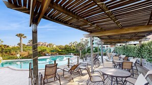 Ein Außenpoolbereich mit Holzterrasse, Liegestühlen und einer Pergola.