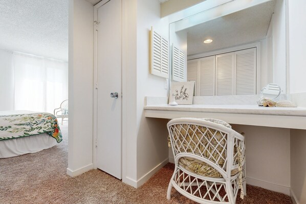 A bedroom with a bed, a desk, a chair, and a door.