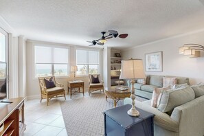 A living room with a large window, a ceiling fan, a sofa, a coffee table, and a TV stand.