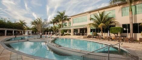 A swimming pool with a curved design, surrounded by lounge chairs and palm trees.