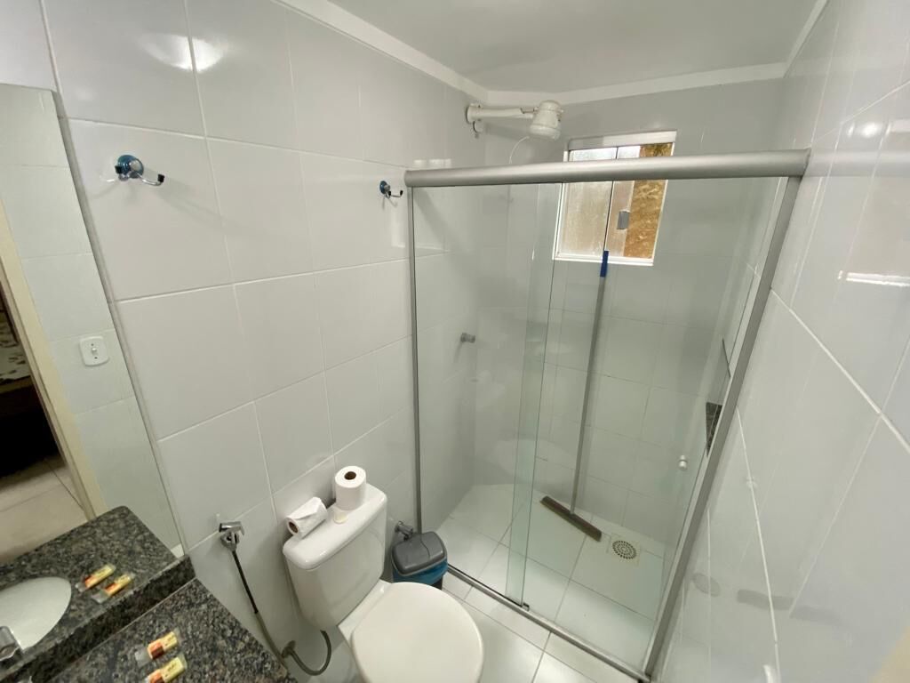 Ein Badezimmer mit Glasdusche, Toilette und einer Waschtischplatte aus Granit mit Toilettenartikeln.