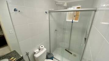 Een badkamer met een douchecabine van glas, een toilet en een granieten aanrechtblad met toiletartikelen.
