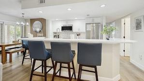 Une cuisine moderne dotée d’un îlot central, de tabourets de bar et d’un coin repas avec une banquette.