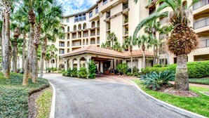 Un hotel con un viale curvo, palme e un ingresso coperto.
