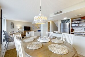 Een moderne keuken met een ronde eettafel, witte stoelen en een kroonluchter.