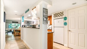 A kitchen with white cabinets, a refrigerator, and a dining area with a table and chairs.