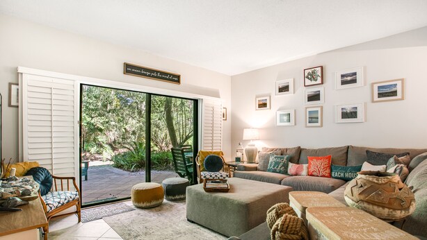 A living room with a large sliding glass door leading to a patio, a sofa set, a coffee table, and a rug.