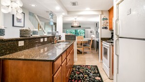 A kitchen with granite countertops, wooden cabinets, a built-in oven, and a refrigerator.