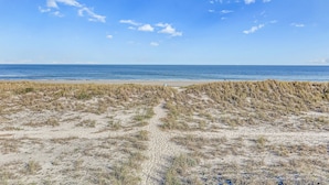 A beach with a clear sky and a sandy path leading to the water. - Oceanfront townhome with a furnished balcony, outdoor pool, & tennis (Fernandina Beach)