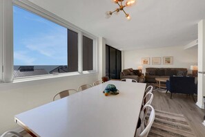 Una sala de estar moderna con un gran ventanal, una mesa de comedor y un sofá.