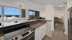 Eine moderne Küche mit einer Granitabdeckung, einem eingebauten Ofen und einem großen Fenster.