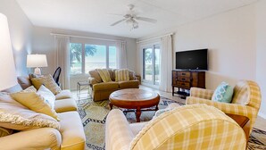 Ein geräumiges Wohnzimmer mit Deckenventilator, zwei Sofas, einem Couchtisch und einem Fernseher.