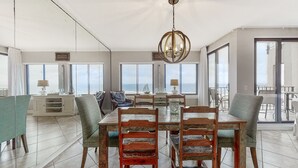 Un vaste espace dédié à la salle à manger, avec une grande table et des chaises, un lustre et de grandes fenêtres offrant une vue panoramique.