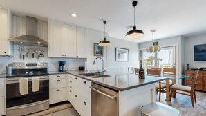 A modern kitchen with white cabinetry, stainless steel appliances, and a central island. - Lovely oceanfront townhouse in Summer Beach Village w/Shared Pool, Central AC (Fernandina Beach)