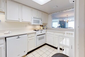A kitchen with white cabinets, a microwave, a stove, and a dishwasher. - Oceanfront condo with spacious balcony, great views, AC & outdoor pool (Fernandina Beach)