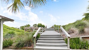 A wooden staircase leading to a covered area, surrounded by lush greenery and a clear sky. - Oceanfront condo with balcony, water views, AC & outdoor pool (Fernandina Beach)