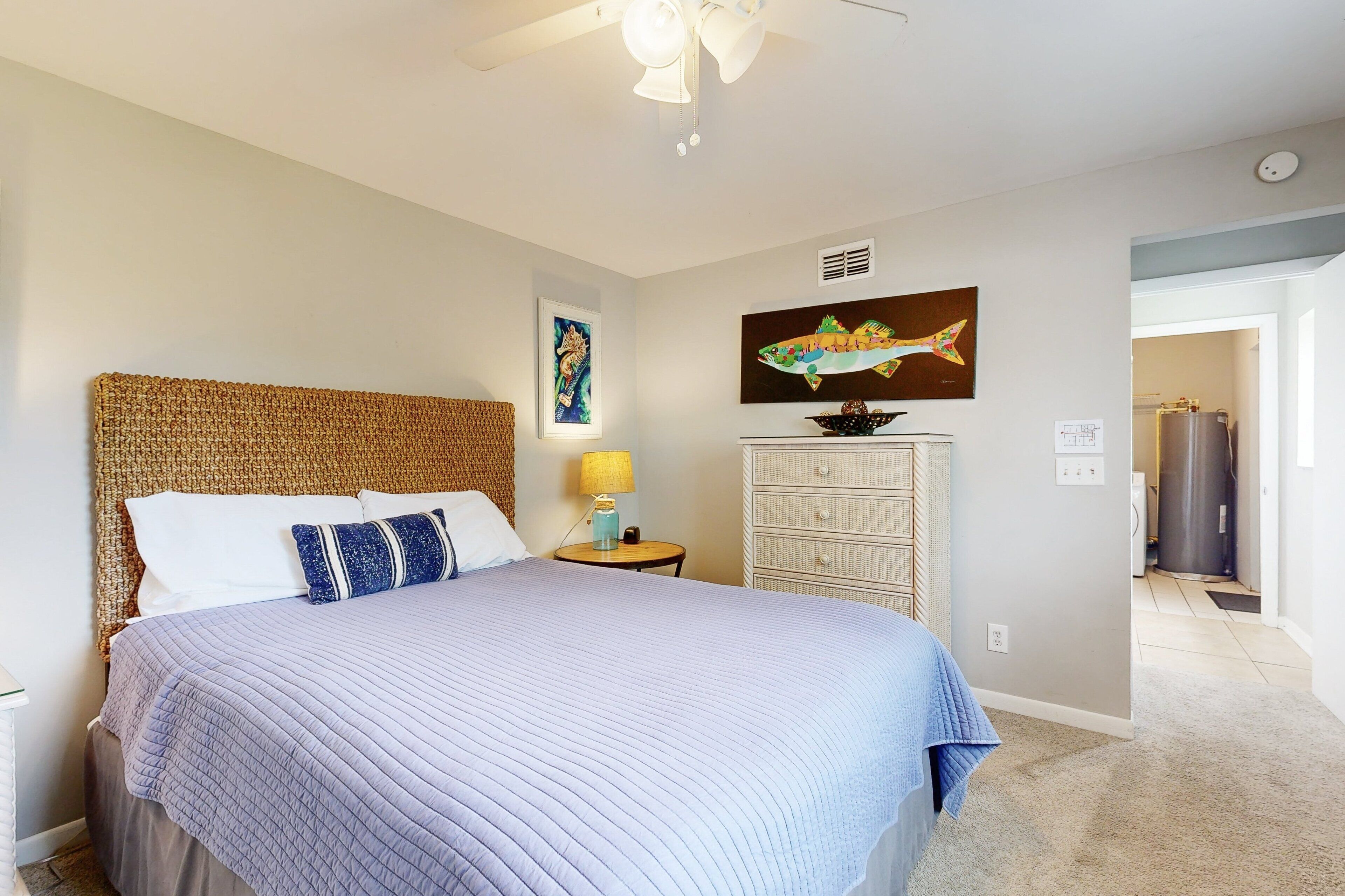 A bedroom with a large bed, a nightstand, a dresser, and a ceiling fan.