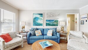 Un soggiorno con un divano blu, due tavolini con lampade, un tavolino da caffè e un tappeto decorato.