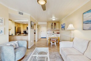 A living room with two sofas, a coffee table, and a dining area with a table and chairs.