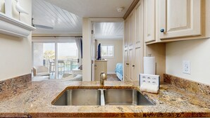Une cuisine dotée de plans de travail en granit, d’un évier double et d’armoires en bois.
