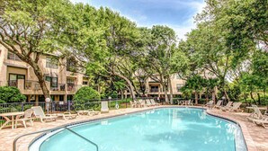 A swimming pool with lounge chairs and a building with balconies in the background. - Newly Renovated Summer Beach Village Home with Patio, WiFi & Shared Pool (Fernandina Beach)