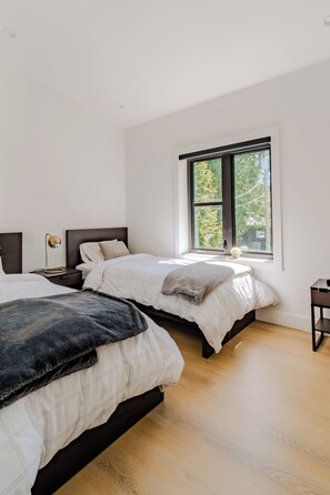 A bedroom with two beds, a window, and a nightstand.